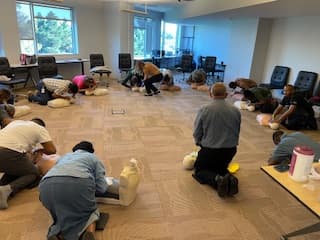 Instructor supervising a CPR training session in a conference room.