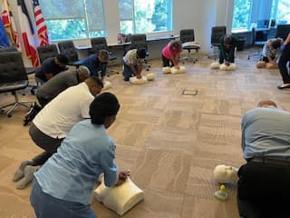 Group CPR class practicing compressions on manikins.